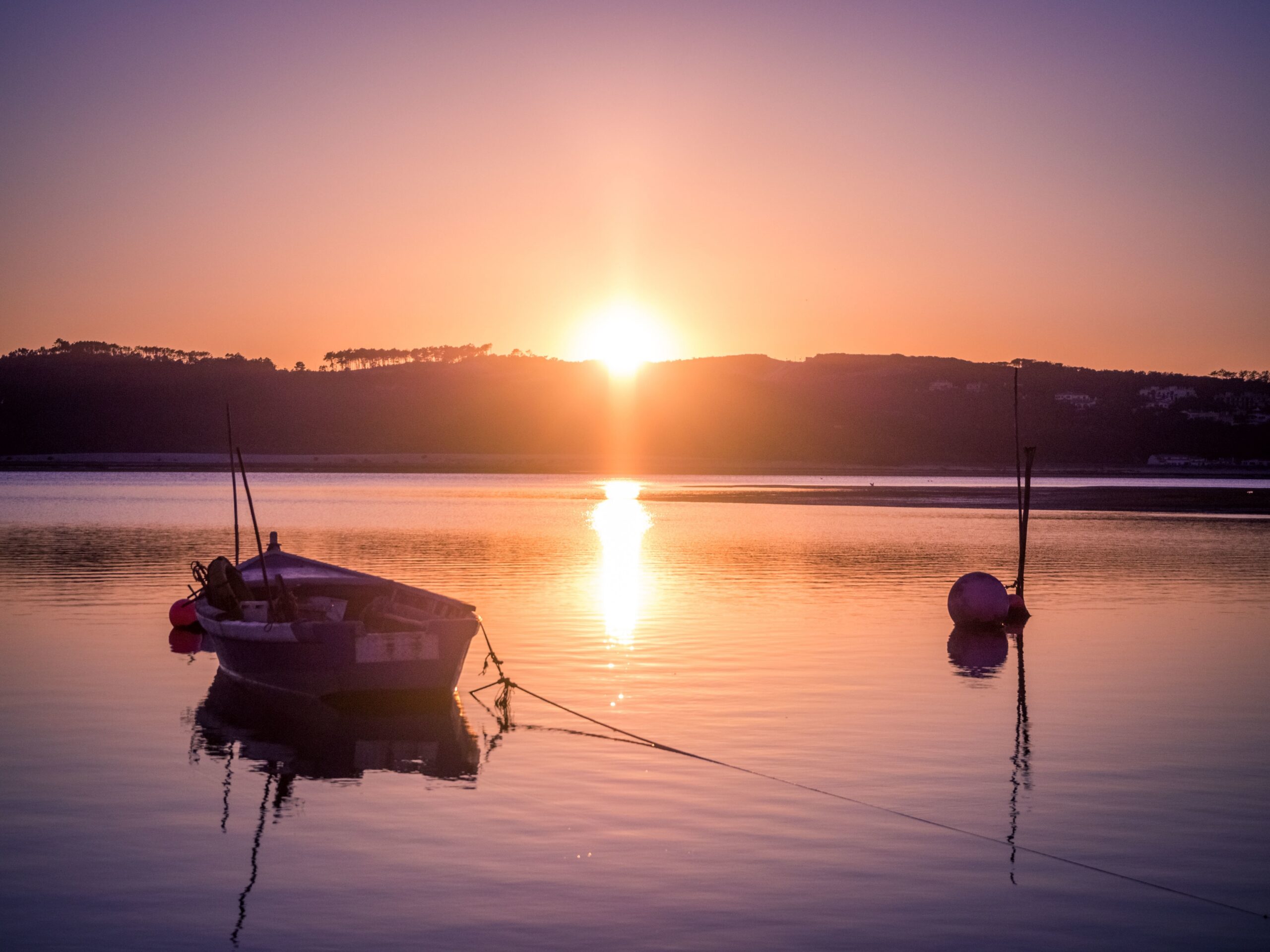 Home old fishing boat at the river with the breathtaking view of the sunset in the background